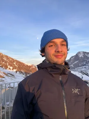 Portrait d'Adrien Lutz en bonnet, montagnes enneigées derrière lui